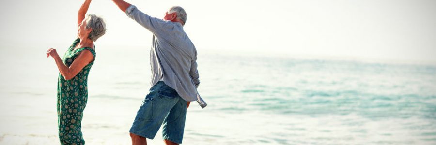 Senior couple dancing at beach on sunny day